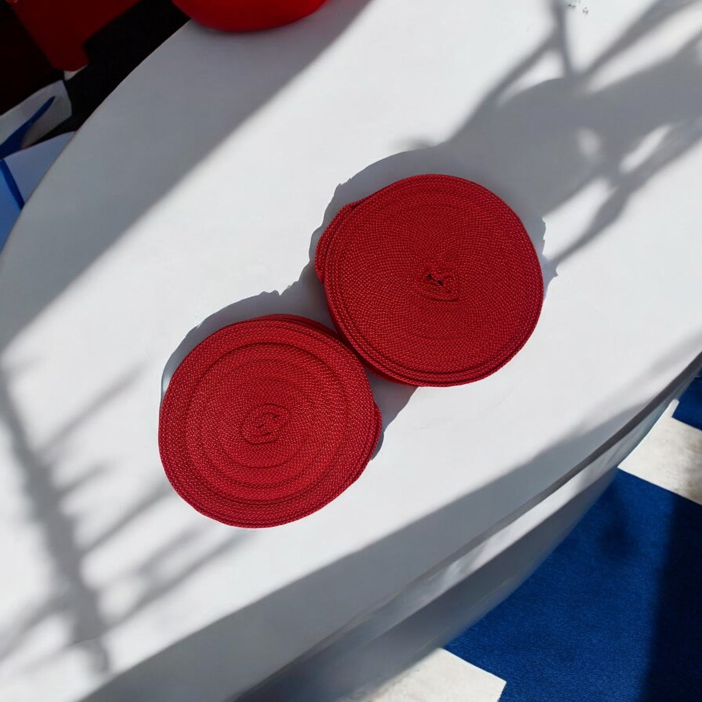 Bandes de boxe SIMSPORT couleur rouge posées sur un sol blanc salle de boxe en arrière plan