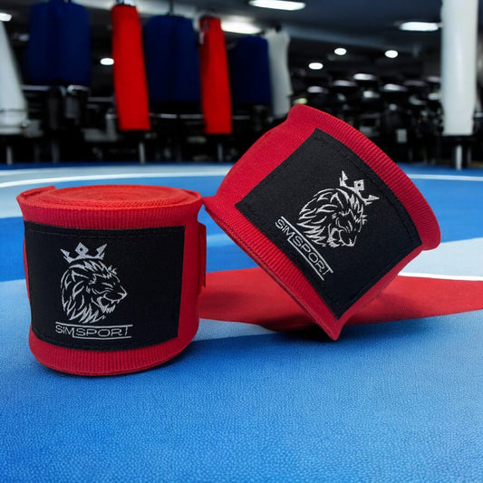 Bandes de boxe SIMSPORT couleur rouge posées sur un sol couleur France salle de boxe en arrière plan, sacs de frappe
